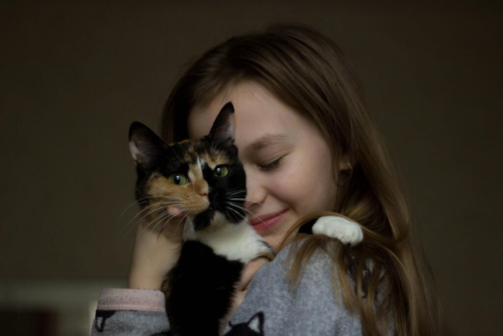 pexels photo 1945539 1945539 A young girl lovingly hugs a calico cat indoors, showing affection and friendship.